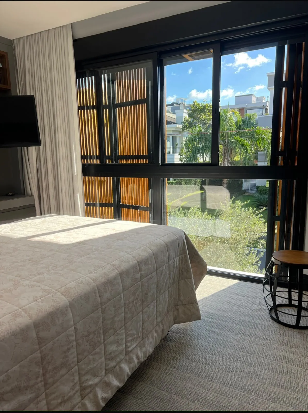 Suíte com esquadrias pretas e vista para o jardim