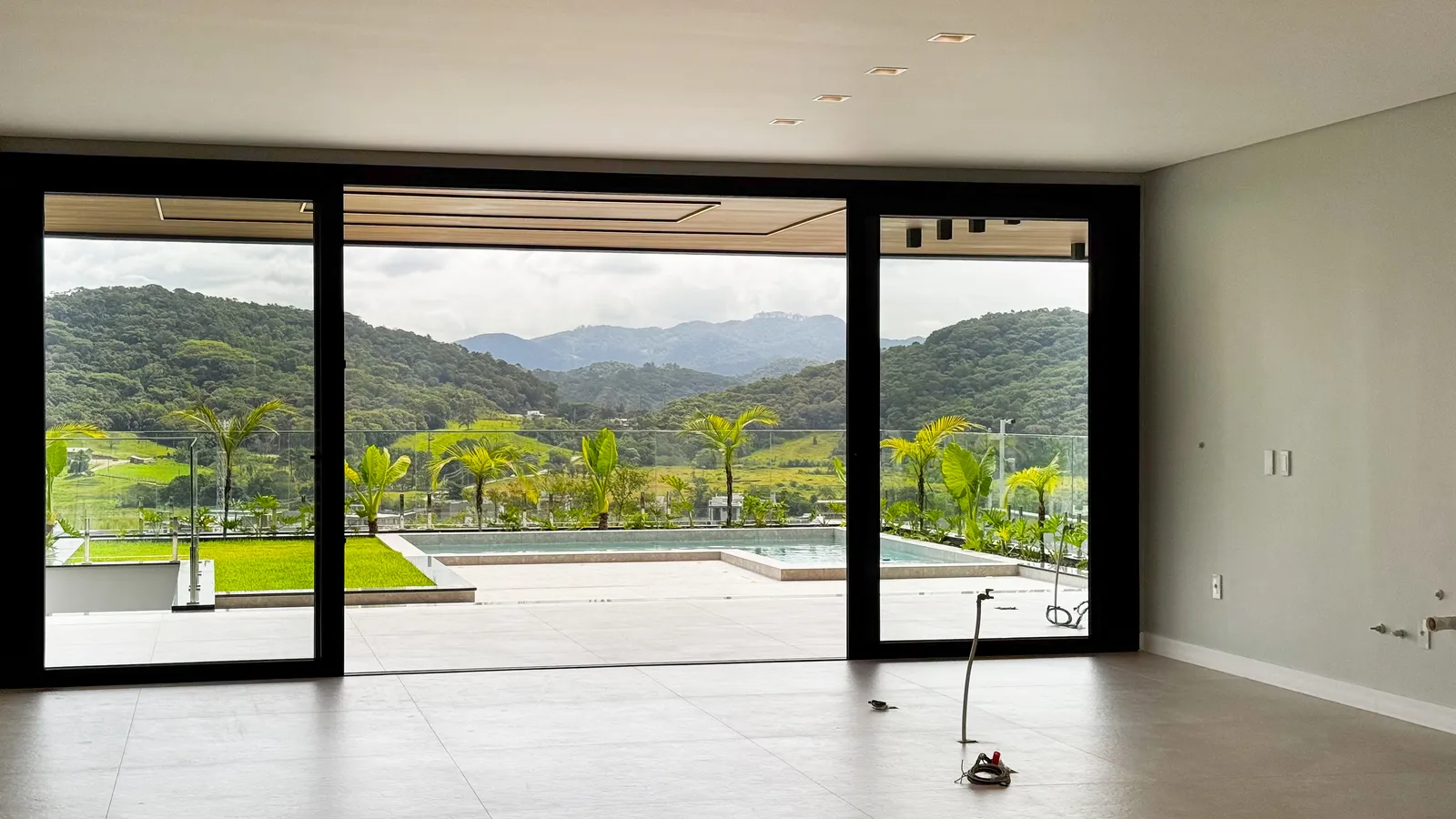 Living da Casa Van Gogh com vidro do piso ao teto e vista panorâmica para a serra e o vale