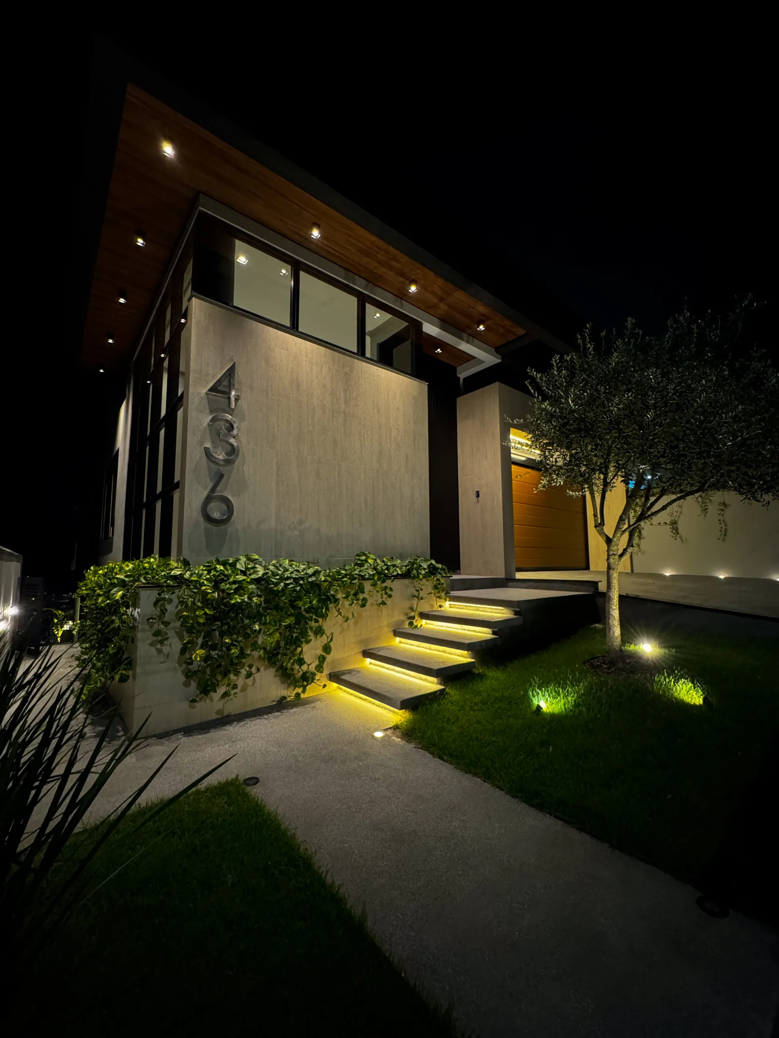 Entrada da Casa Van Gogh iluminada à noite, com paisagismo e o número 436