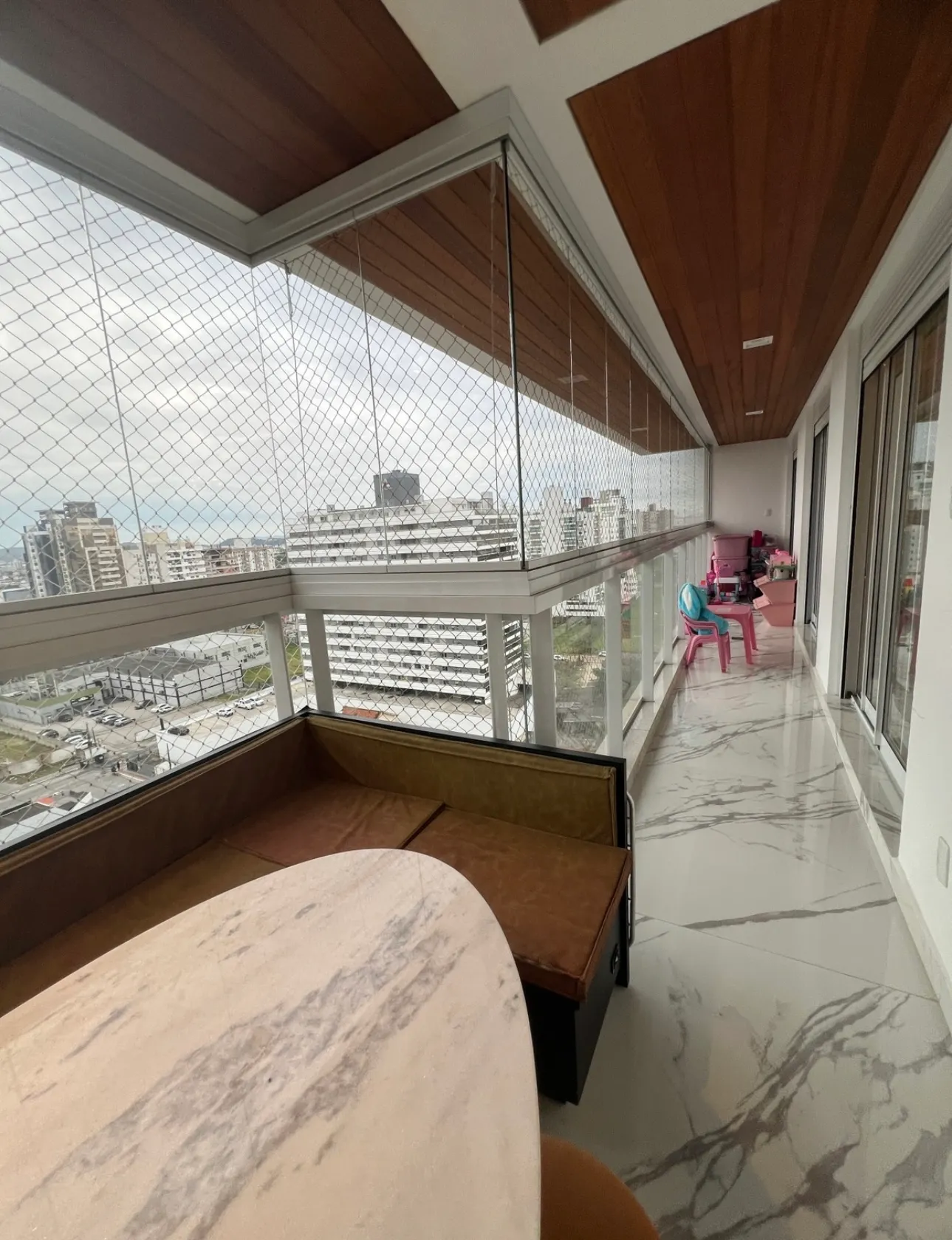 Ampla sacada do apartamento no Lux Residence com forro de madeira e vista panorâmica da cidade